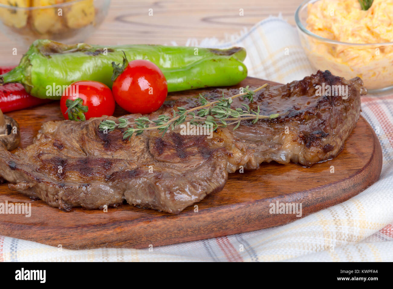 Vista dettagliata di yummy gustosa bistecca alla brace servite sul piatto di legno con di patata e di pomodoro e peperone rosso. Foto Stock