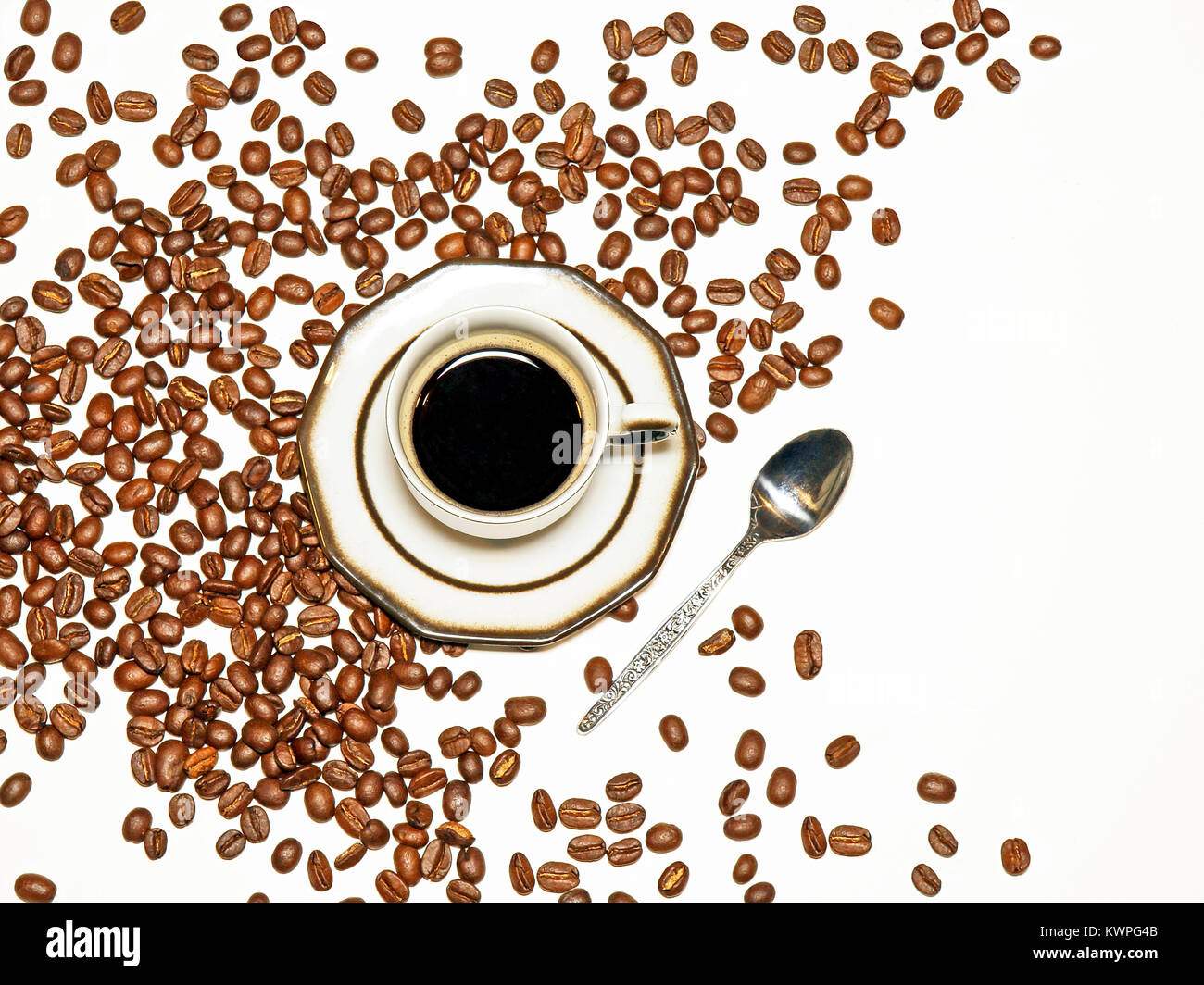 Tazza di caffè espresso su sfondo bianco con i chicchi di caffè sparsi, con spazio libero a destra sul lato dell'immagine. Foto Stock