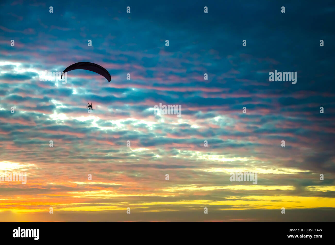 Parapendio motorizzato battenti fino ad alta sul Cielo di tramonto Foto Stock