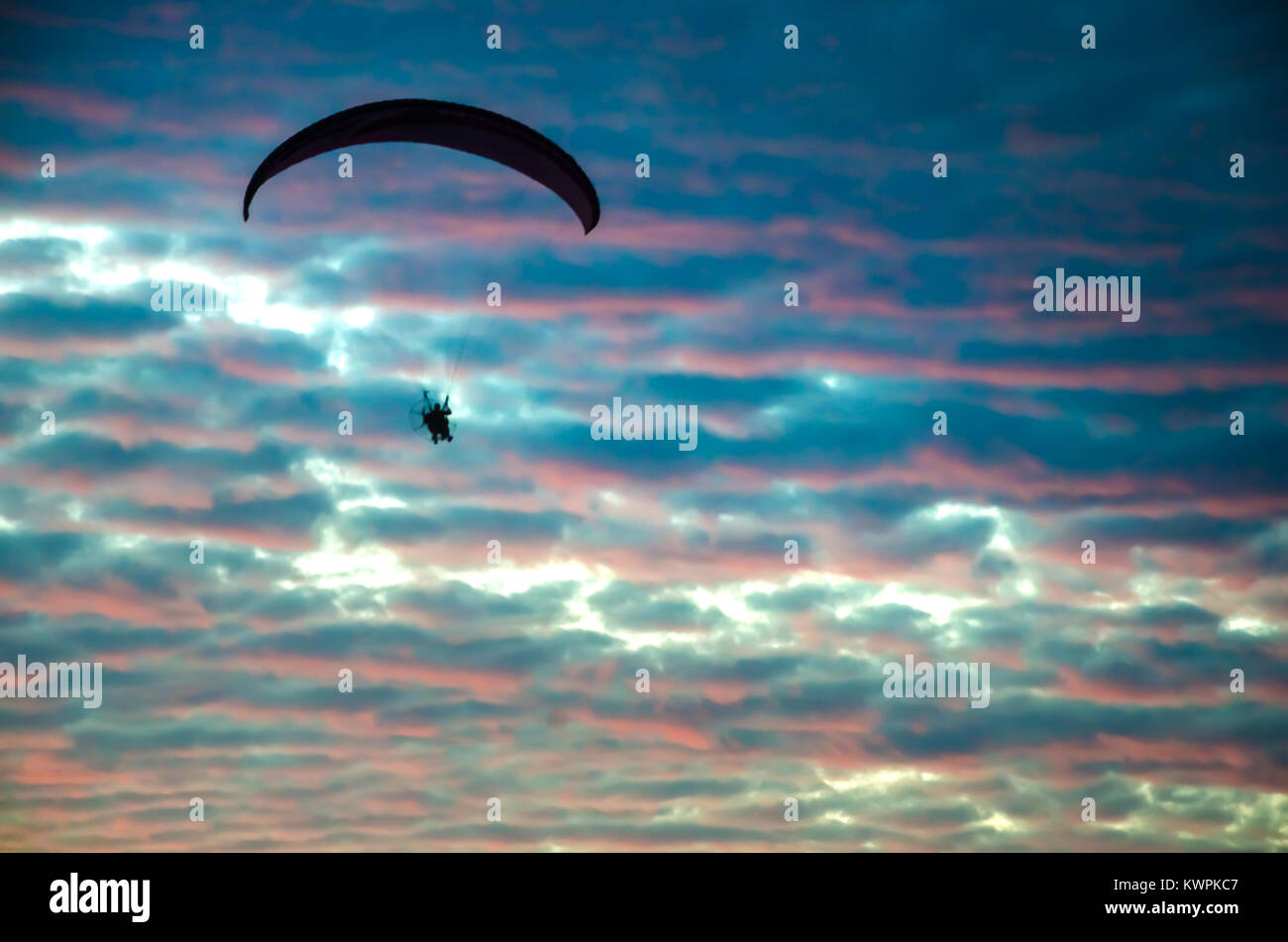 Parapendio motorizzato battenti fino ad alta sul Cielo di tramonto Foto Stock
