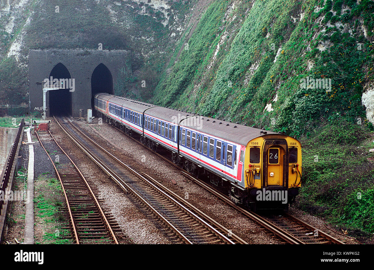 Una coppia di rete di classe a sud-est 411 4 CEP EMU numeri 1588 e 1567 emergono da Shakespeare Cliff tunnel tra Dover e Folkestone. Dal 8 aprile 1993. Foto Stock