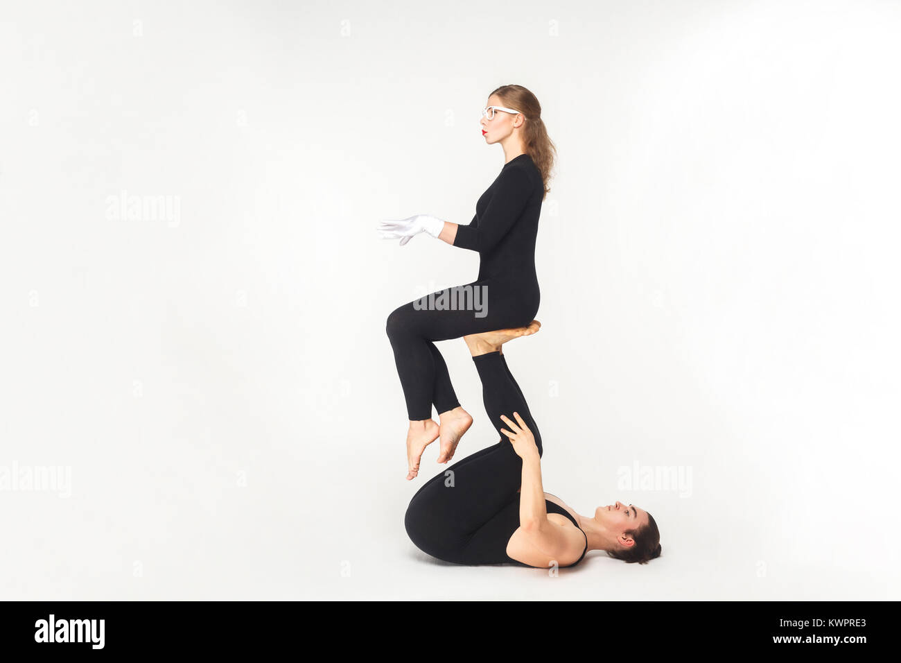 Concetto acrobatico, sedersi pongono. Giovane donna di contenimento gambe, bilanciamento. Studio shot, isolato su sfondo bianco Foto Stock
