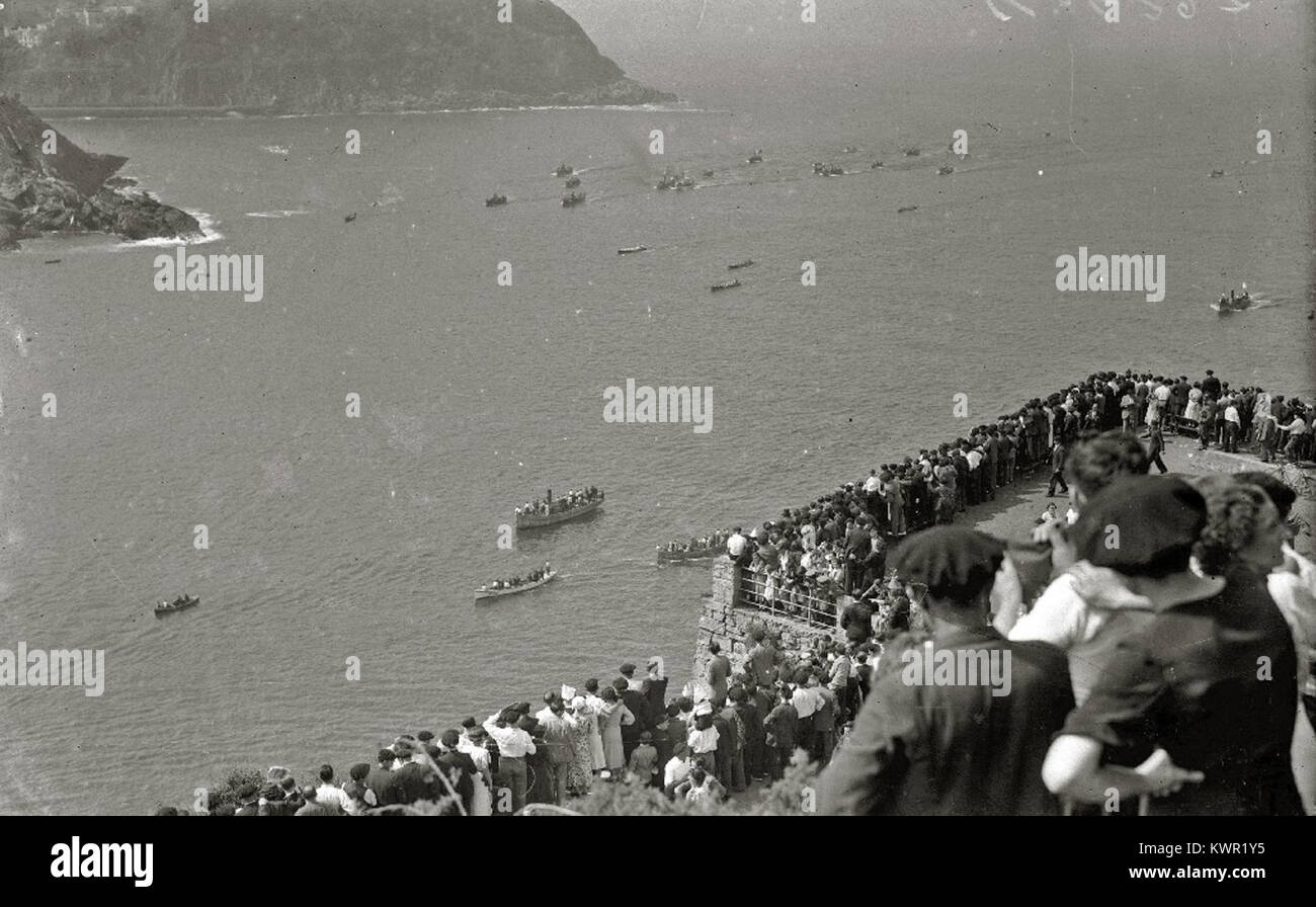 Un'immagine della collezione Car-Kutxa Fototeka mostra una tradizionale regata di traineras nella baia di la Concha, evidenziando un evento marittimo competitivo radicato nella cultura costiera spagnola. Foto Stock