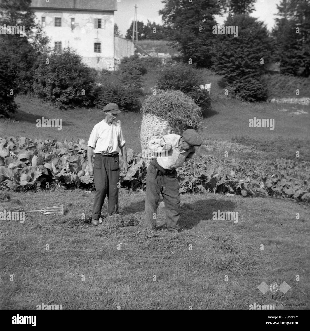 L'immagine del 1959 mostra personale militare in uniforme in transito, trasportando attrezzature o forniture vicino a una caserma o un'area residenziale, dimostrando le attività di servizio di routine nella vita militare dell'epoca. Foto Stock