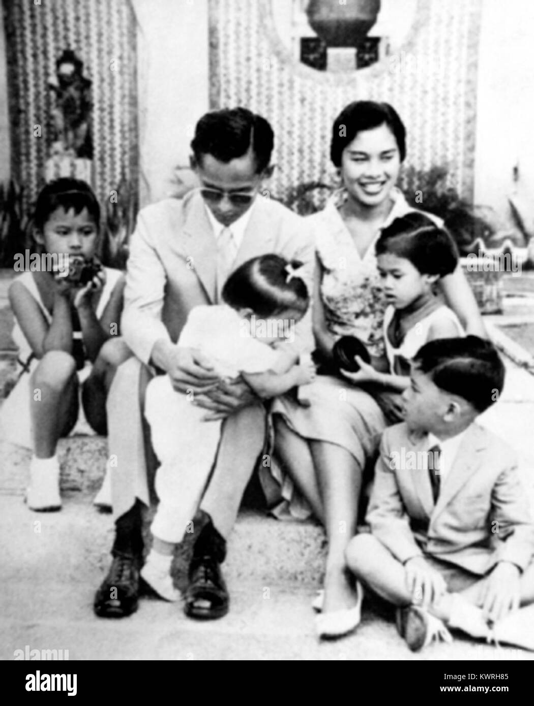Una fotografia del 1958 del re Bhumibol Adulyadej, la regina Sirikit, e il loro figlio, il principe ereditario Vajiralongkorn di Thailandia. L'immagine cattura la famiglia reale tailandese durante un'occasione ufficiale o pubblica, riflettendo l'importanza della monarchia nella Thailandia della metà del XX secolo. Foto Stock