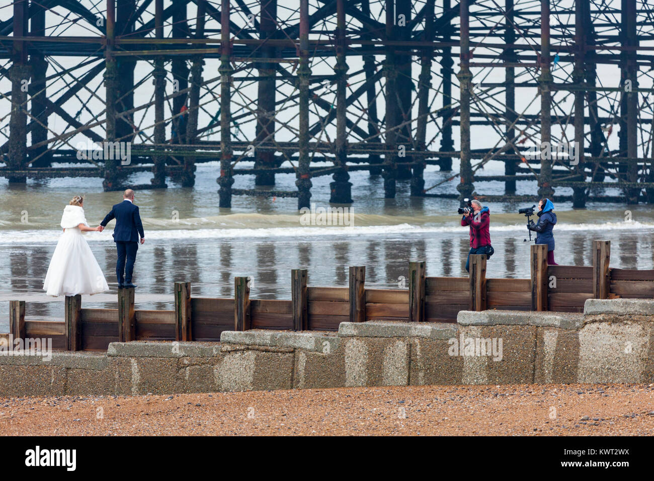 Hastings, East Sussex, Regno Unito. Il 6 gennaio, 2018. Nuvoloso e leggermente piccante per iniziare la giornata in Hastings con un sacco di persone facendo una passeggiata lungo la spiaggia come la marea è fuori al momento. Questa felice coppia in abiti da cerimonia posa per foto sulla spiaggia vicino a pilastri di Hastings Pier. Photo credit: Paolo Lawrenson/Alamy Live News Foto Stock