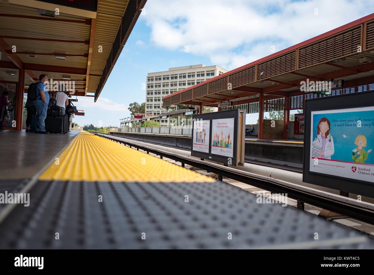 A basso angolo di visione dei passeggeri in attesa di un treno, visto dal bordo della piattaforma, all'Walnut Creek, California stazione della Bay Area Rapid Transit (BART) Sistema ferroviario leggero, 13 settembre 2017. Foto Stock
