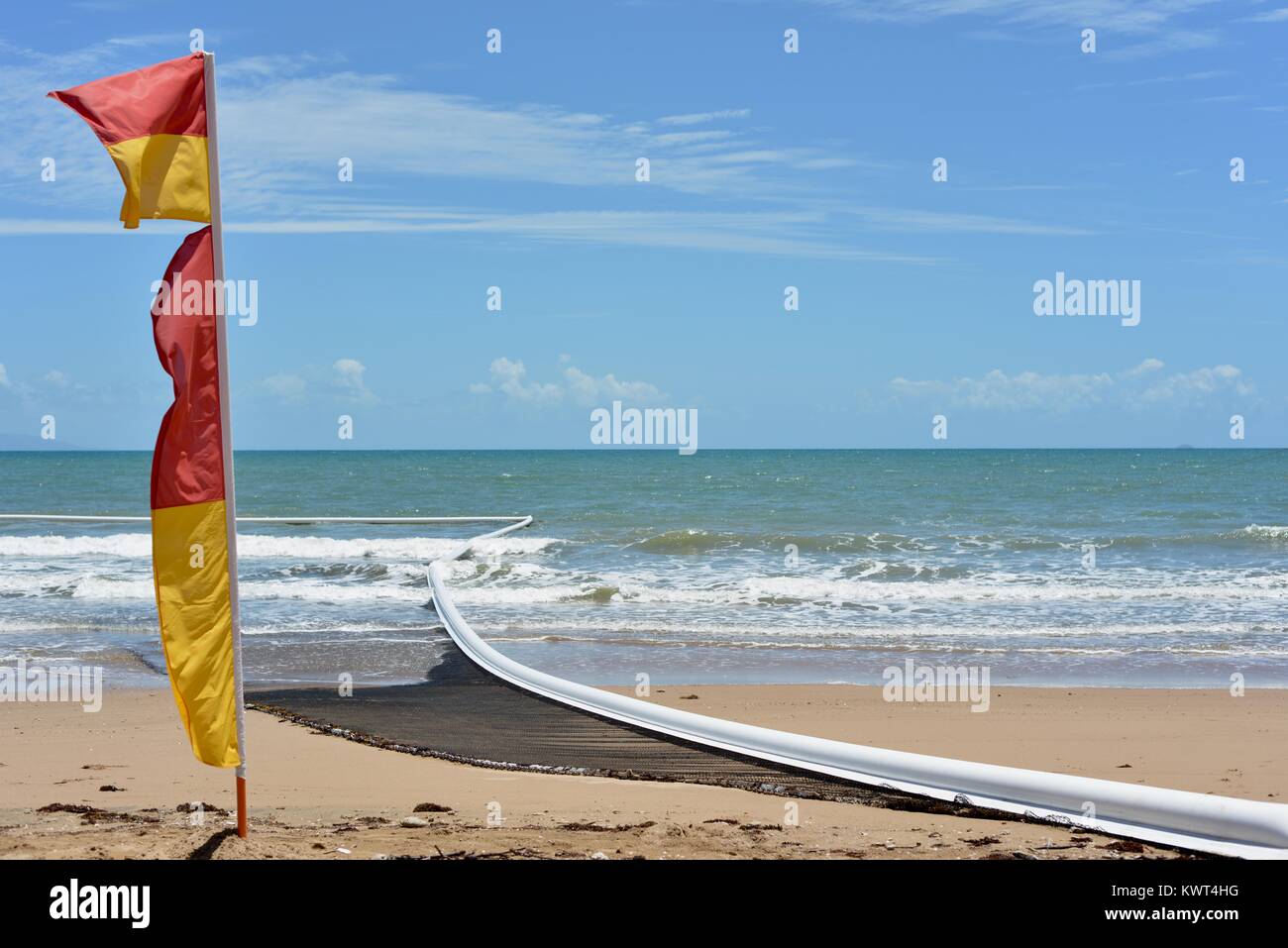 Rosso e giallo surf lifesaving bandiera con meduse reti in background, Bagal spiaggia vicino a Townsville, Queensland, Australia Foto Stock