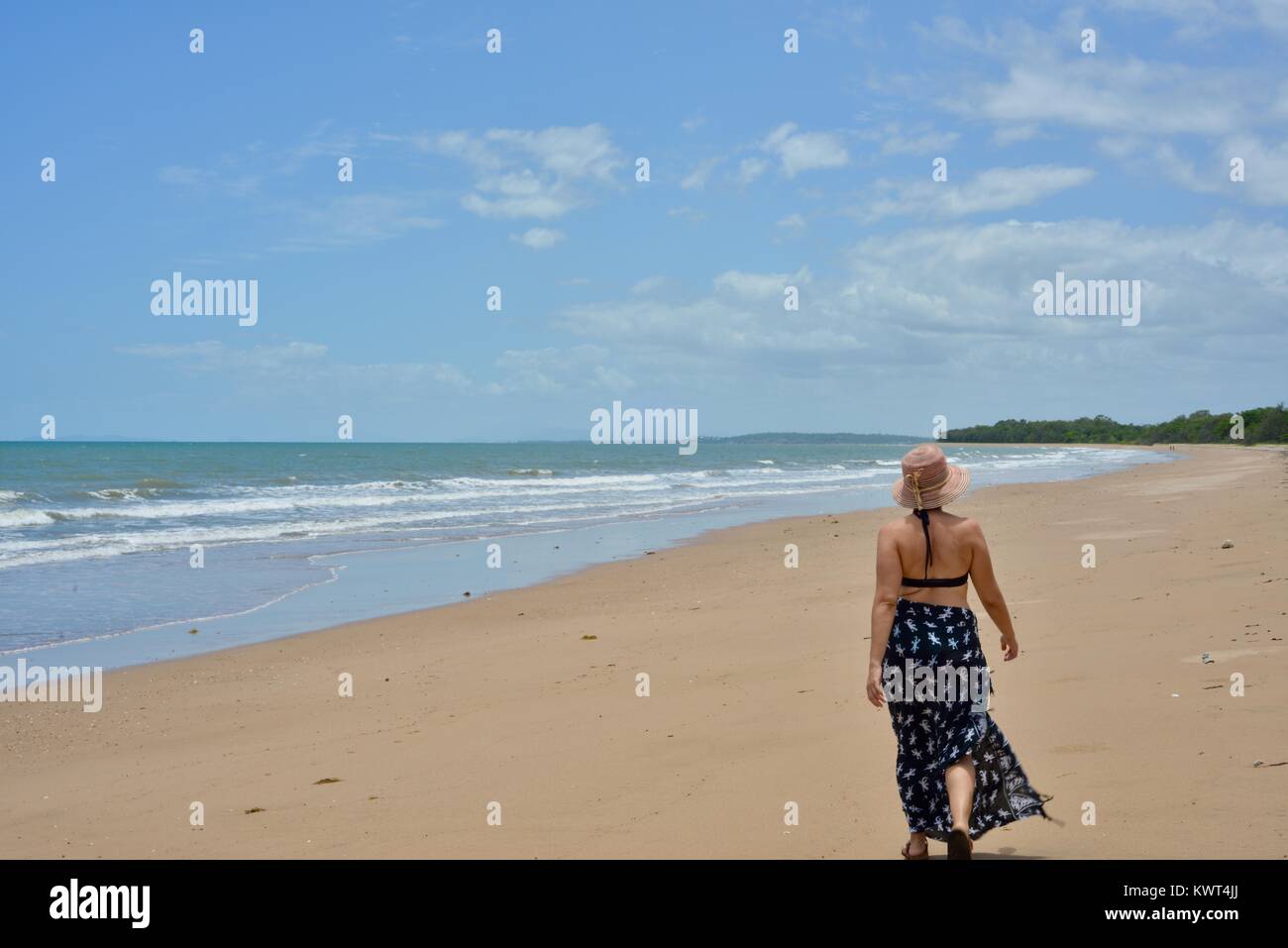 Donne camminare da solo in una remota spiaggia tropicale, Balgal Beach, Queensland, Australia Foto Stock