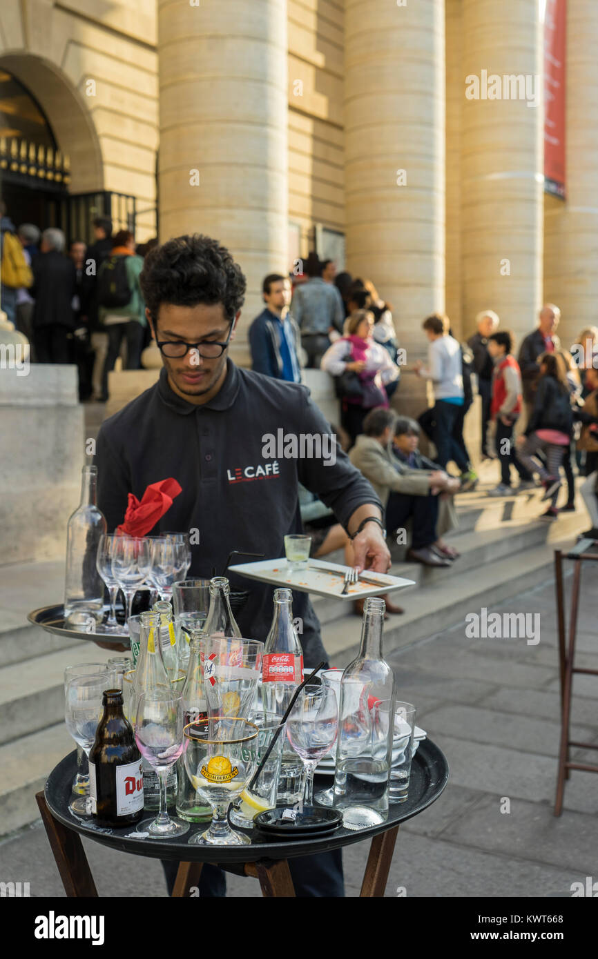 Francia, Parigi, Teatro Odeon de l'Europe cafe , Server raccogliere bottiglie vuote e bicchieri. Foto Stock