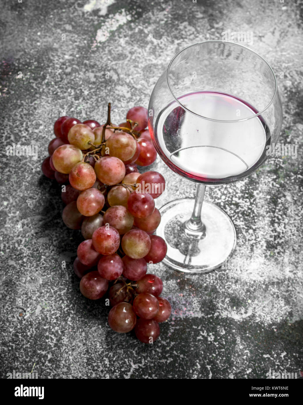 Bicchiere di vino rosso con un ramo di uve fresche. Su uno sfondo rustico. Foto Stock