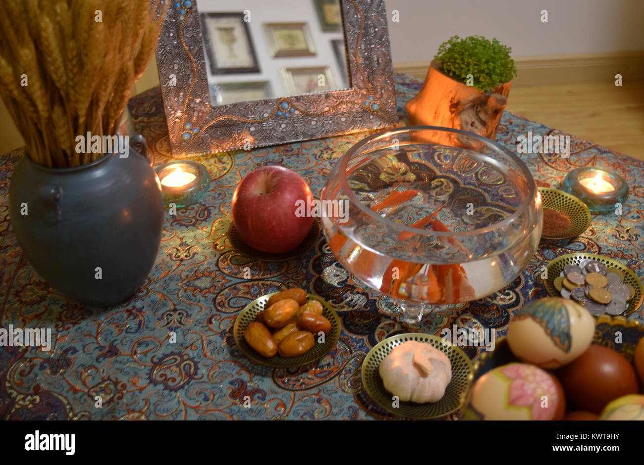 Tabella a lume di candela sparsi per il persiano iraniano nuovo anno celebrazione Norouz compresi artigianato tradizionale di prodotti tessili e il pesce dorato in una ciotola Foto Stock
