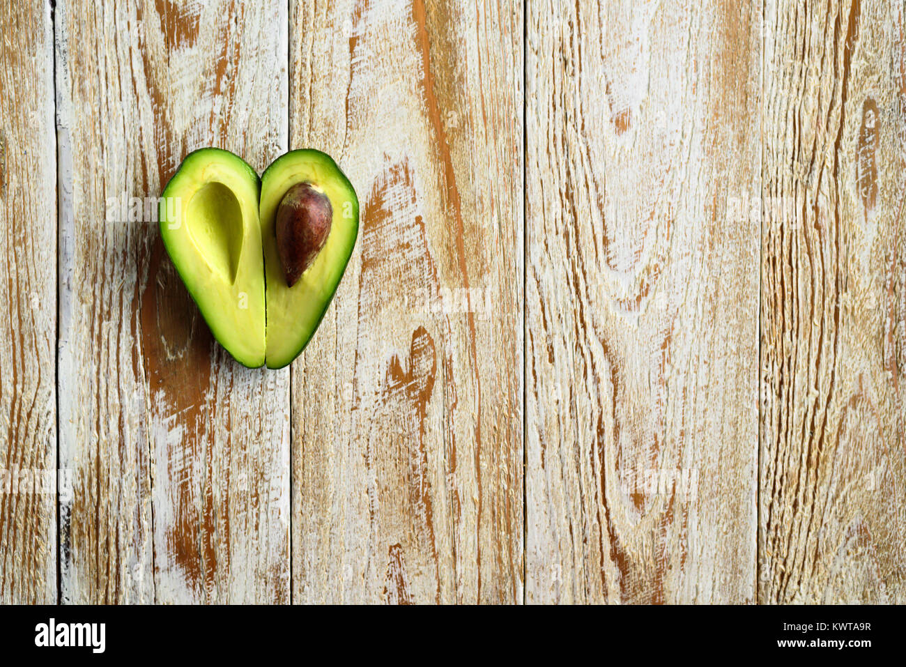 A forma di cuore la metà di avocado su sfondo di legno Foto Stock