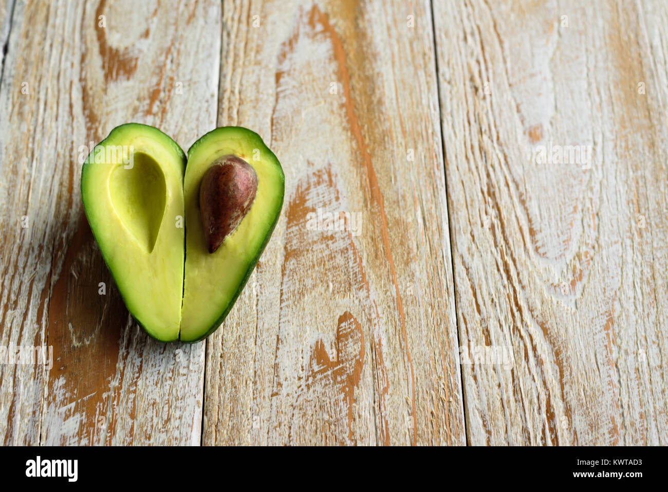 A forma di cuore la metà di avocado su sfondo di legno Foto Stock