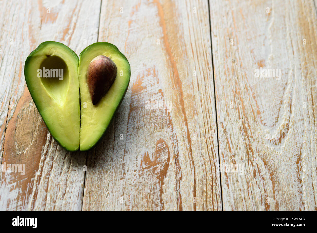 A forma di cuore la metà di avocado su sfondo di legno Foto Stock