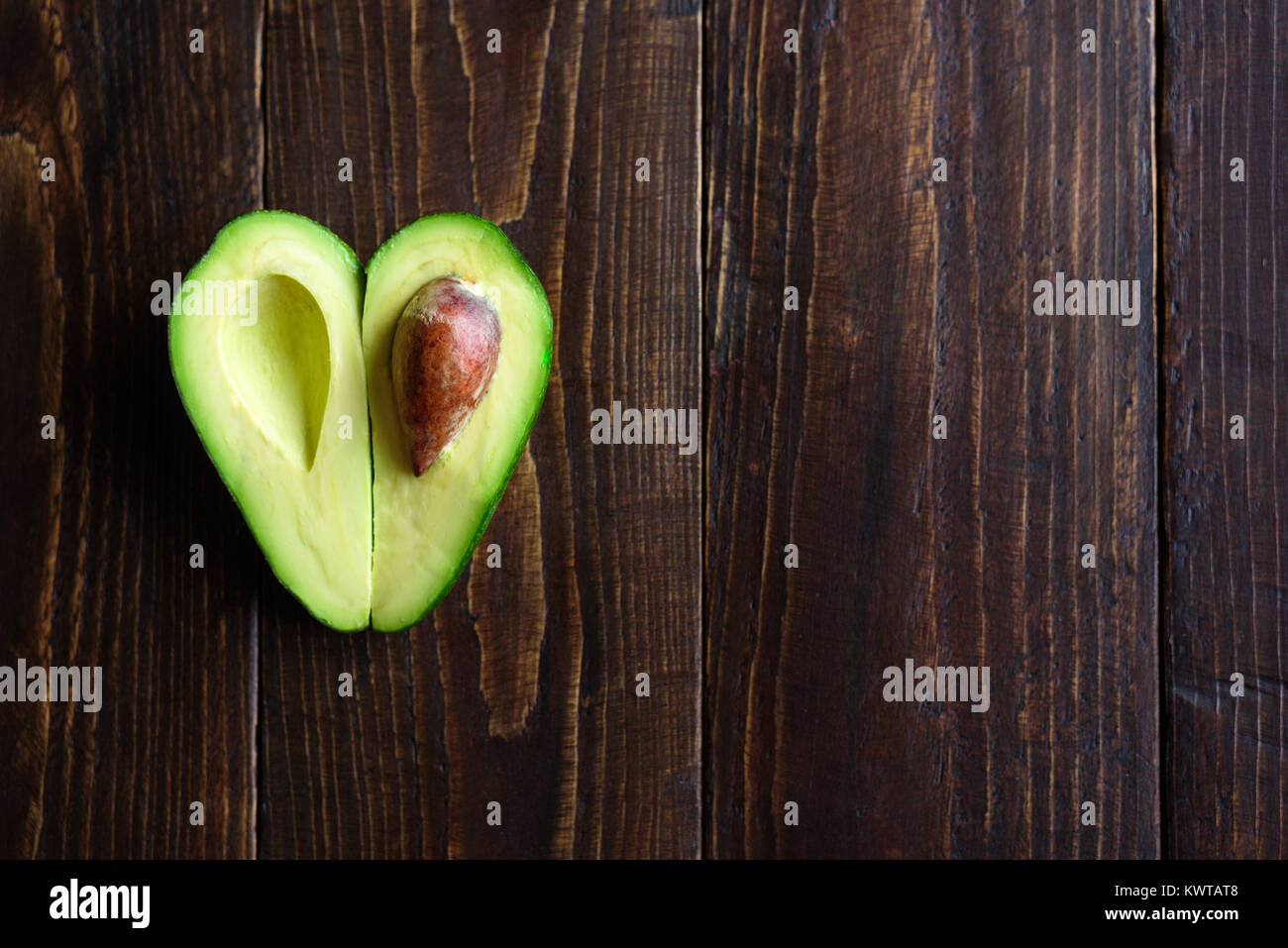 A forma di cuore la metà di avocado su sfondo di legno Foto Stock