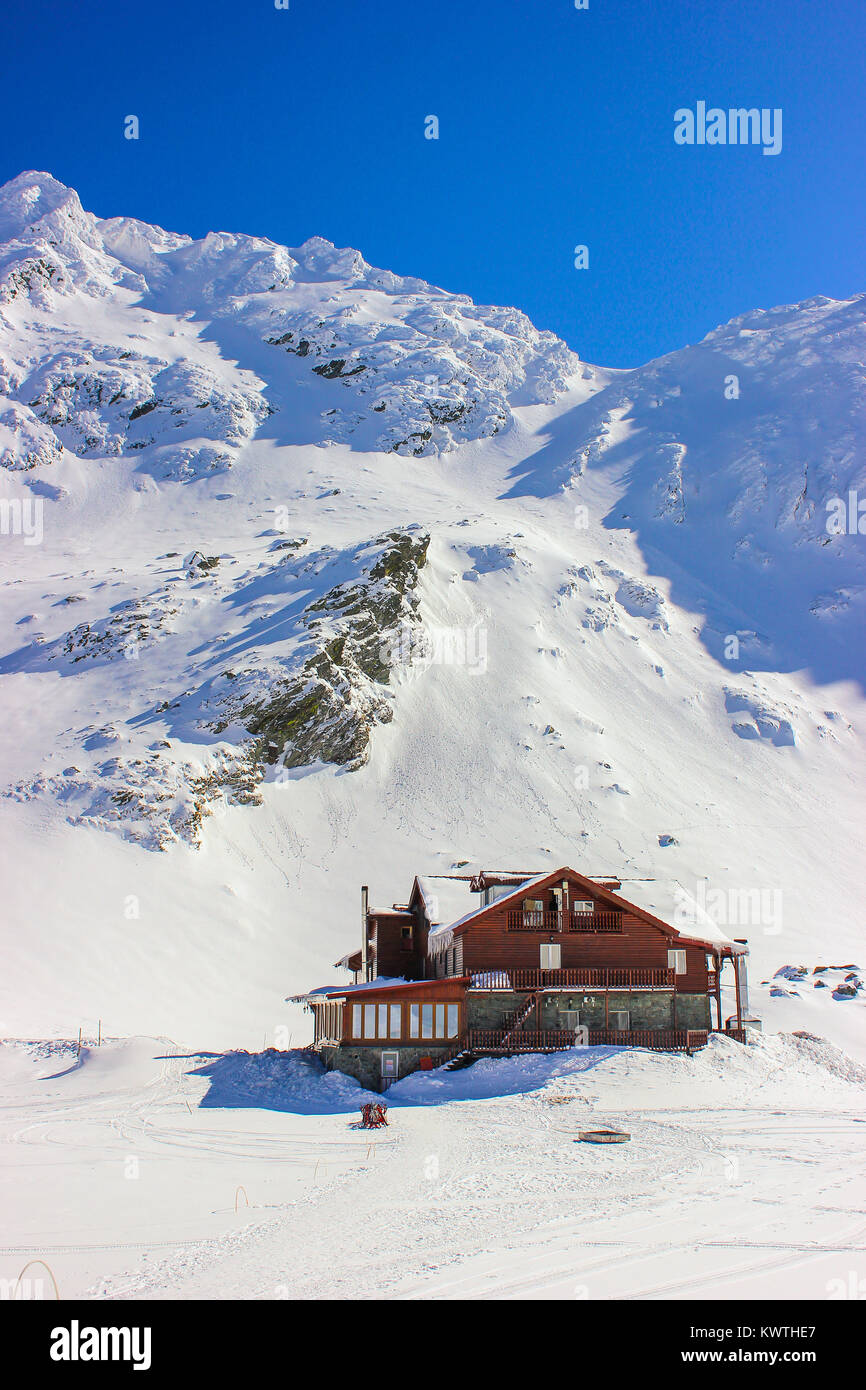 Alpine paesaggio invernale con cabina al lago Balea Fagaras e montagne coperte di neve nella contea di Sibiu, Romania Foto Stock