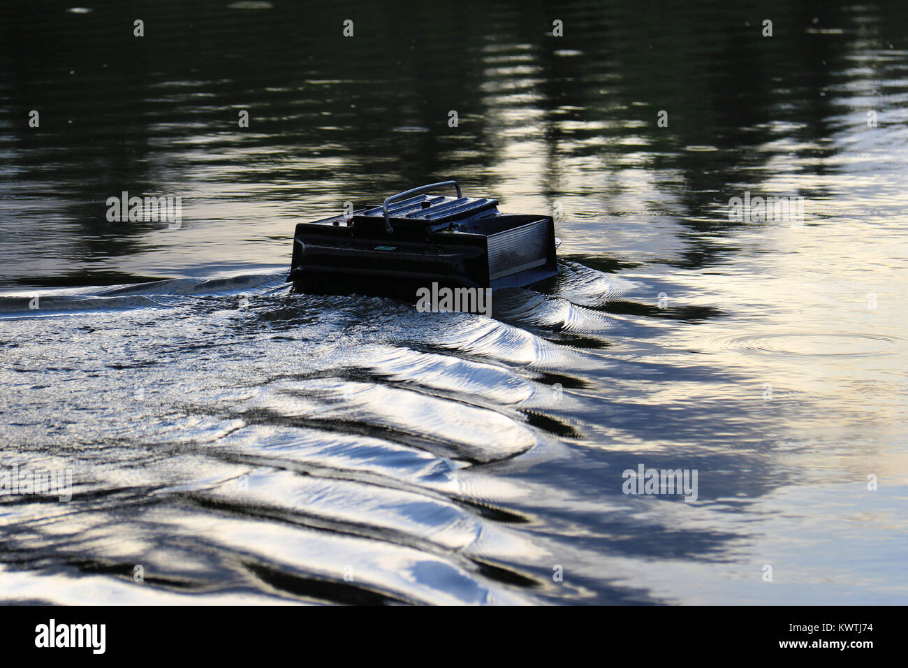 Un telecomando alimentatore controllato in barca in un lago utilizzato nella pesca sportiva. Foto Stock