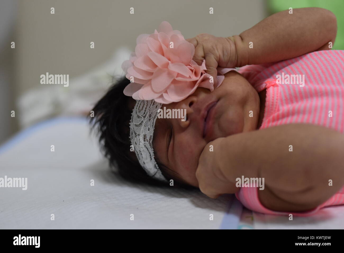 Dark scuoiati neonato ragazza in abiti rosa che stabilisce con gli occhi chiusi Foto Stock