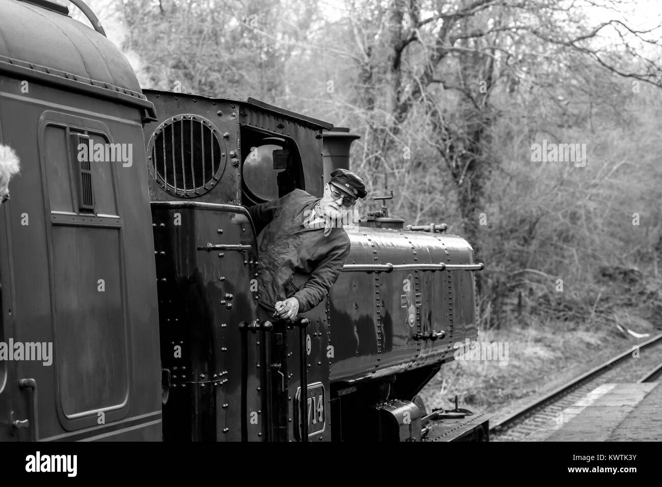 Bianco & Nero close up vintage UK locomotiva a vapore 7714 sulla linea ferroviaria con driver di motore sul pavimento appoggiato al di fuori del treno. Tutti a bordo! Foto Stock