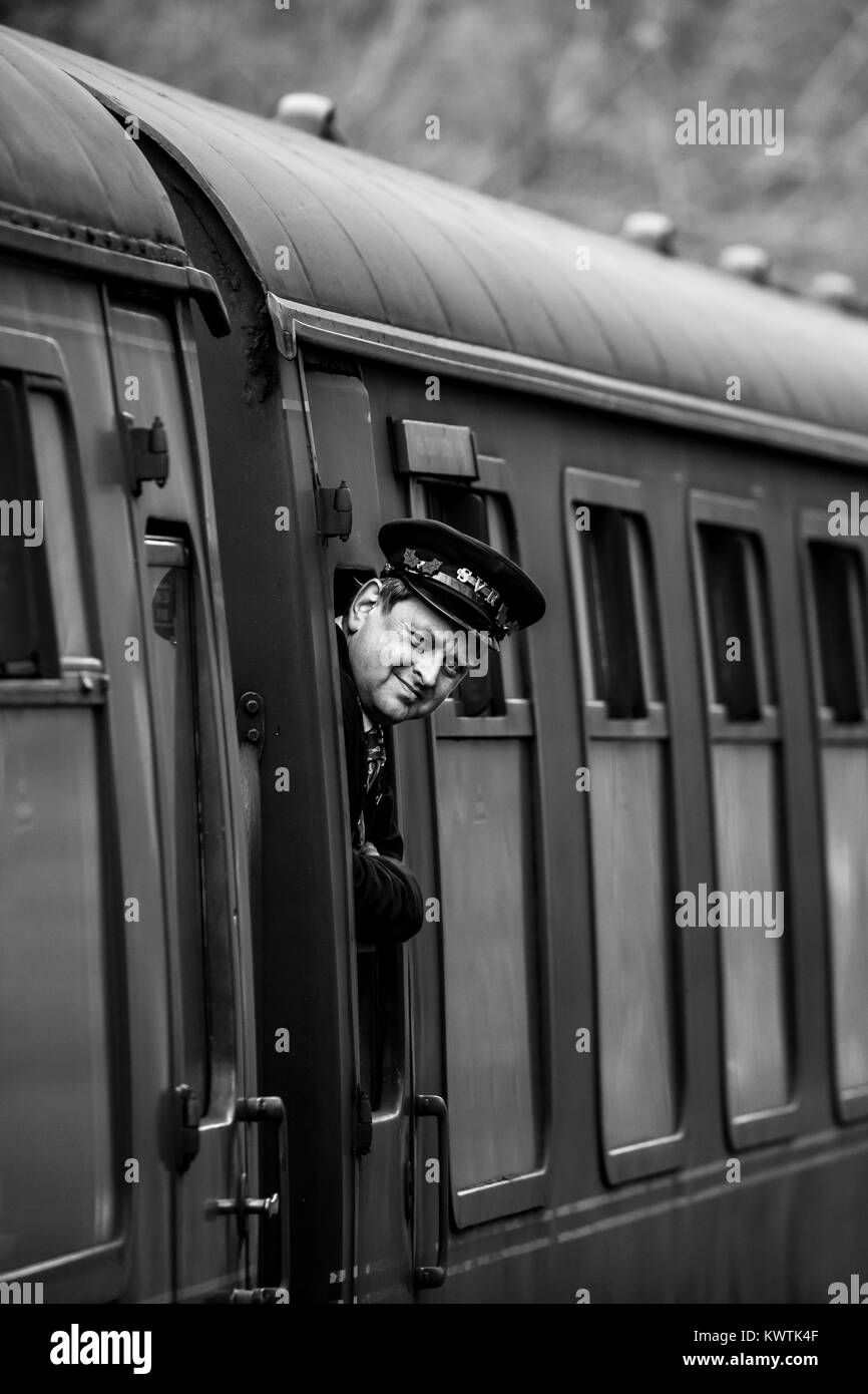 In bianco e nero di close-up shot di sorridere guardia, con cappuccio SVR, proteso al di fuori della finestra per controllare tutti i è sicuro per treno per procedere sul suo cammino. Foto Stock