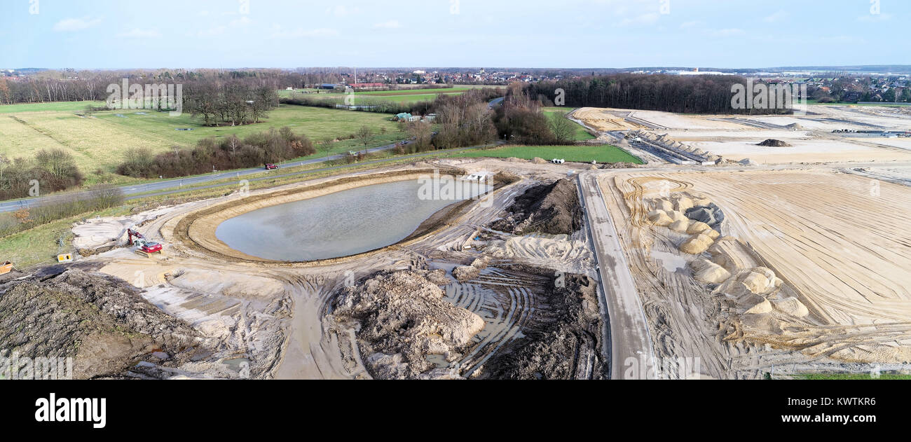 Vista aerea di un sito di costruzione di una nuova area di sviluppo con un nuovo bacino di ritenzione dell'acqua piovana a grande altezza, con un drone Foto Stock