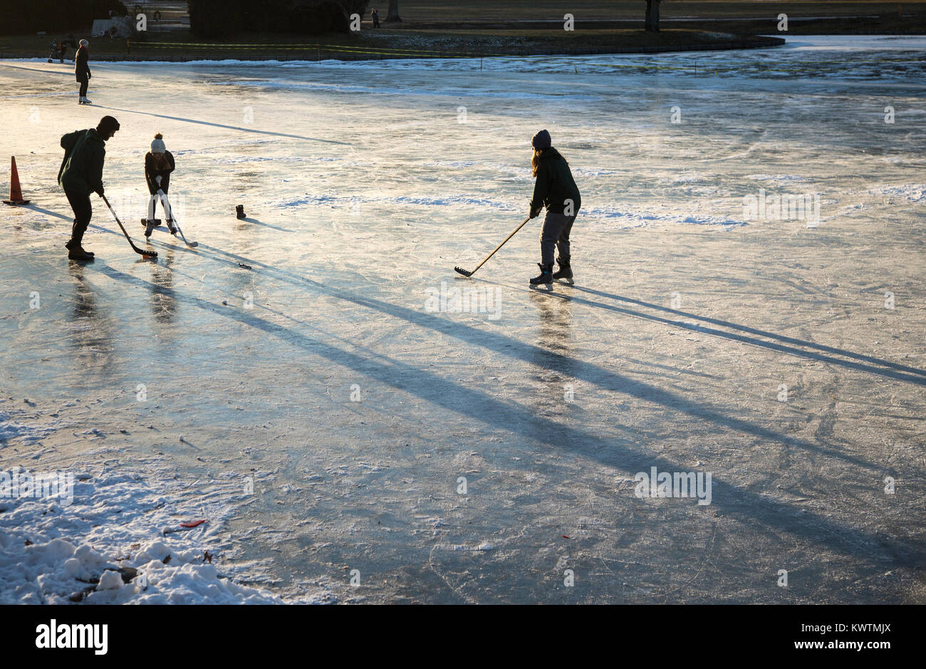 Giocatori di hockey su ghiaccio su un laghetto nel tardo pomeriggio Foto Stock