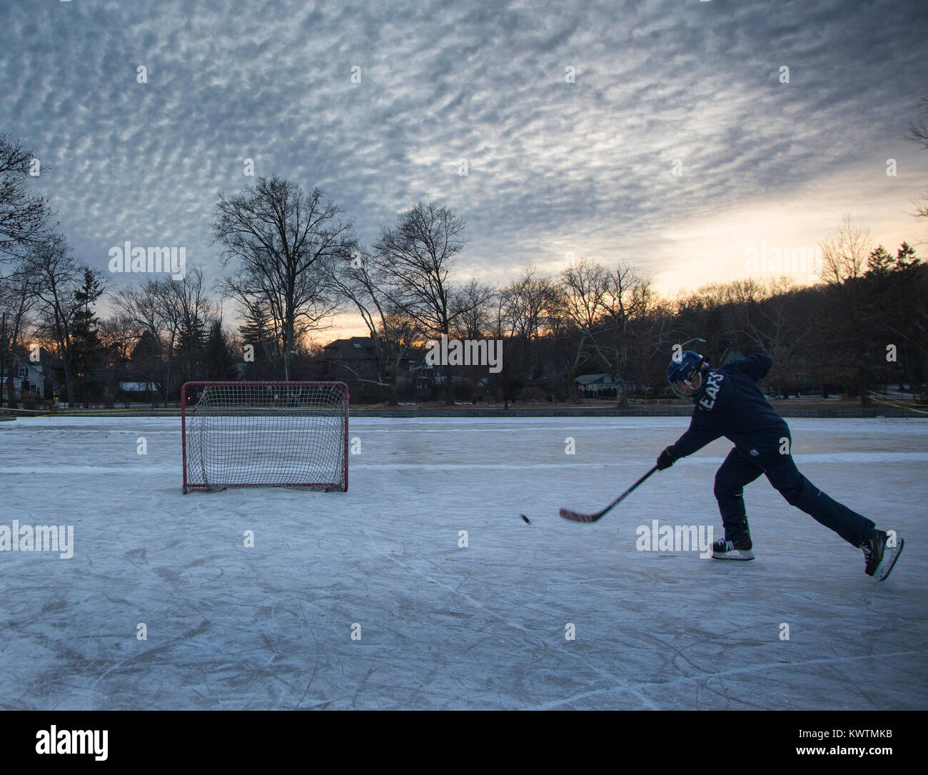 Hockey su ghiaccio di tiro del giocatore un puck su un laghetto congelato Foto Stock
