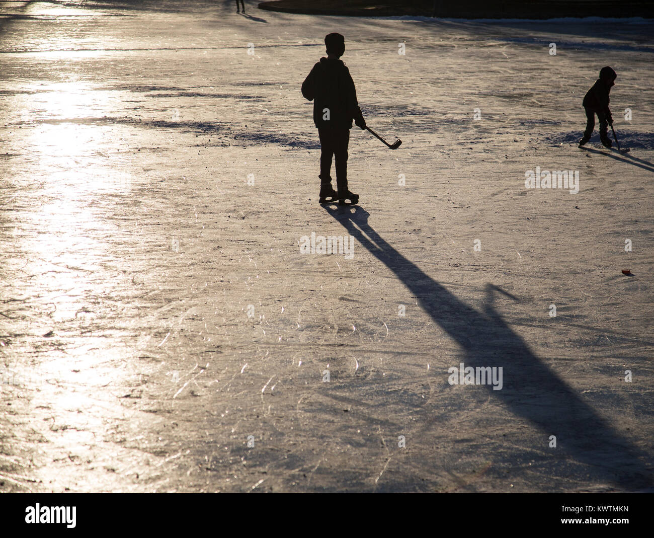 Giocatori di hockey su ghiaccio su un laghetto nel tardo pomeriggio Foto Stock