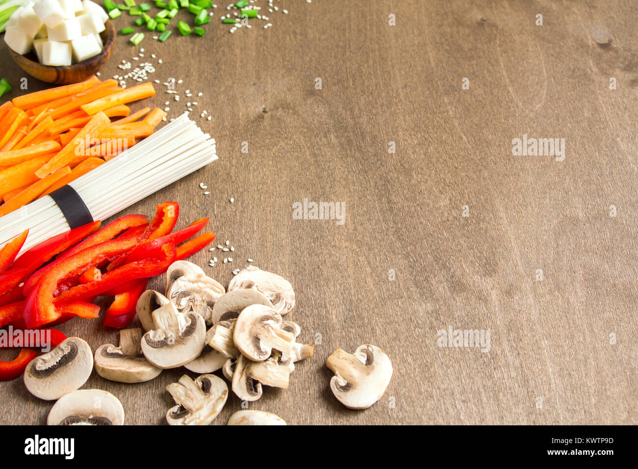 Vegetariano vegano cibo asiatico ingredienti per friggere con tofu, tagliatelle, funghi e verdure sopra lo sfondo di legno con copia spazio. Foto Stock