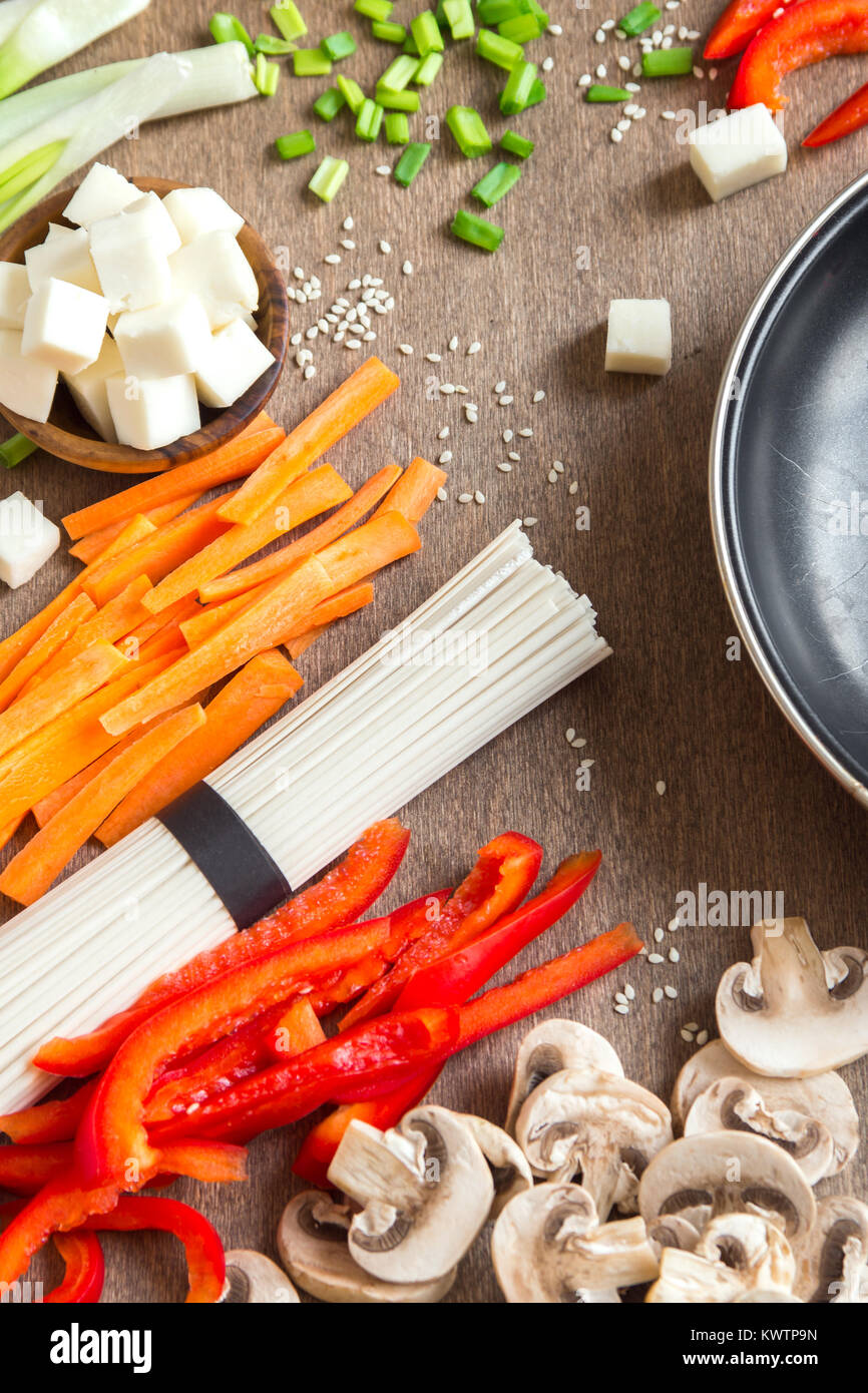 Vegetariano vegano cibo asiatico ingredienti per friggere con tofu, tagliatelle, funghi e verdure sopra lo sfondo di legno con copia spazio. Foto Stock