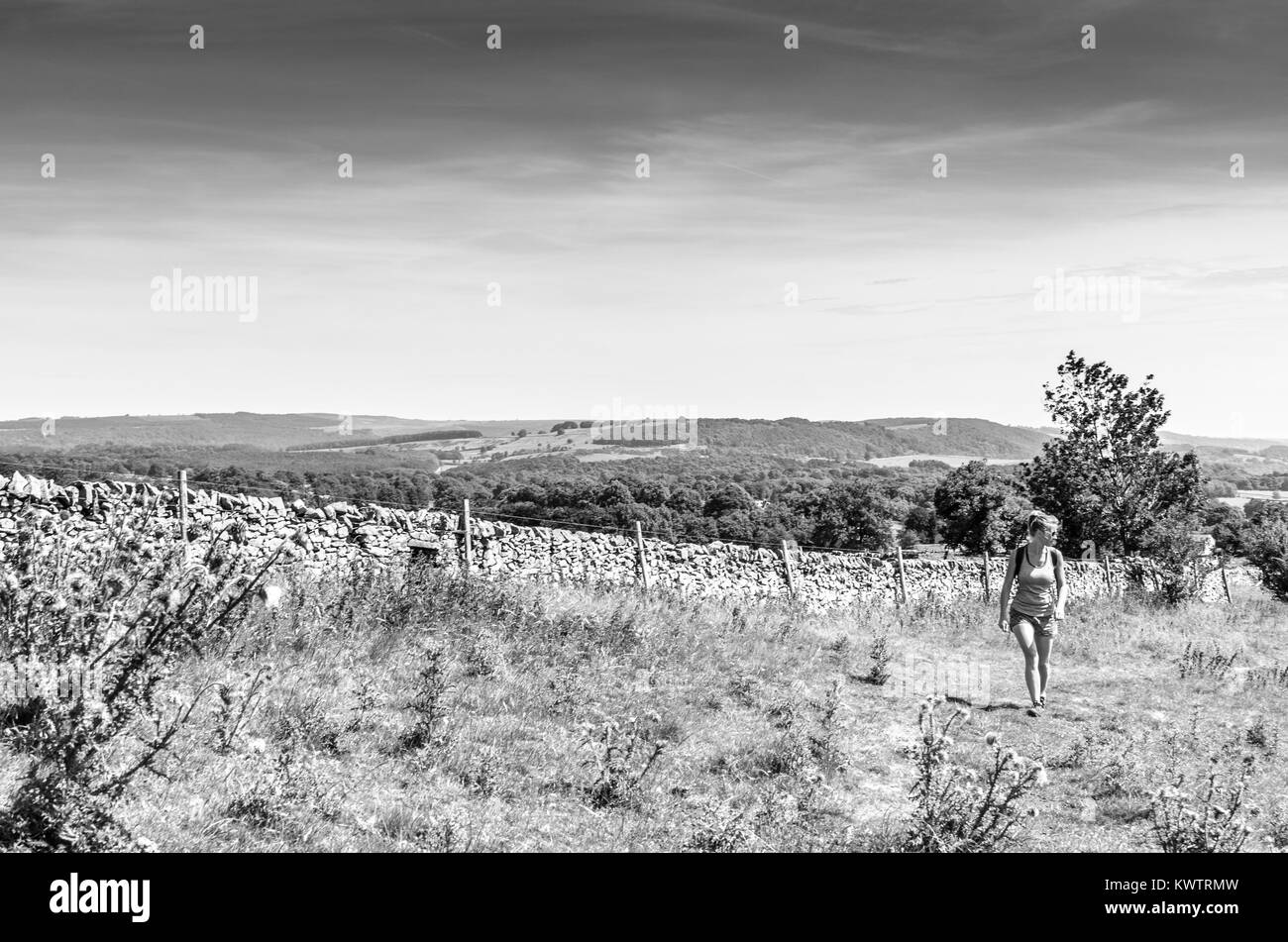 Una giovane donna che cammina da una campagna di recinzione in pietra in inglese il Peak District Foto Stock
