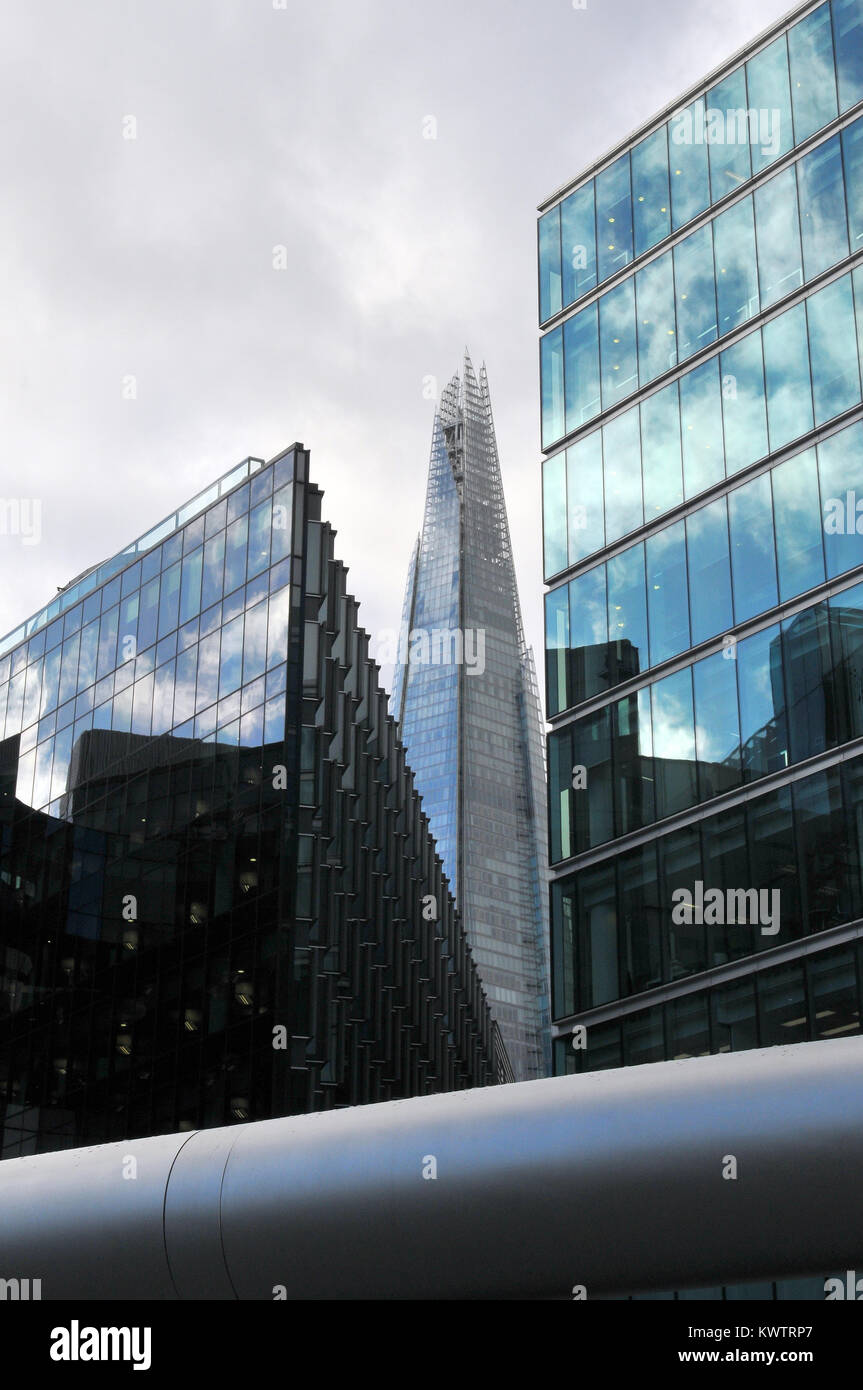 Una diversa o vista insolita della shard da un angolo di alternative tra due edifici per uffici in vetro nel centro di Londra. Cielo tempestoso nuvoloso Foto Stock
