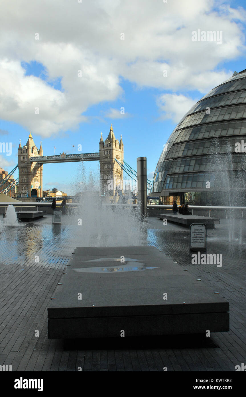 Un display di fontane su un area pavimentata vicino alla city hall e il Tower Bridge sul fiume Tamigi a Londra. Differenti, punto di vista inusuale Tower bridge Foto Stock