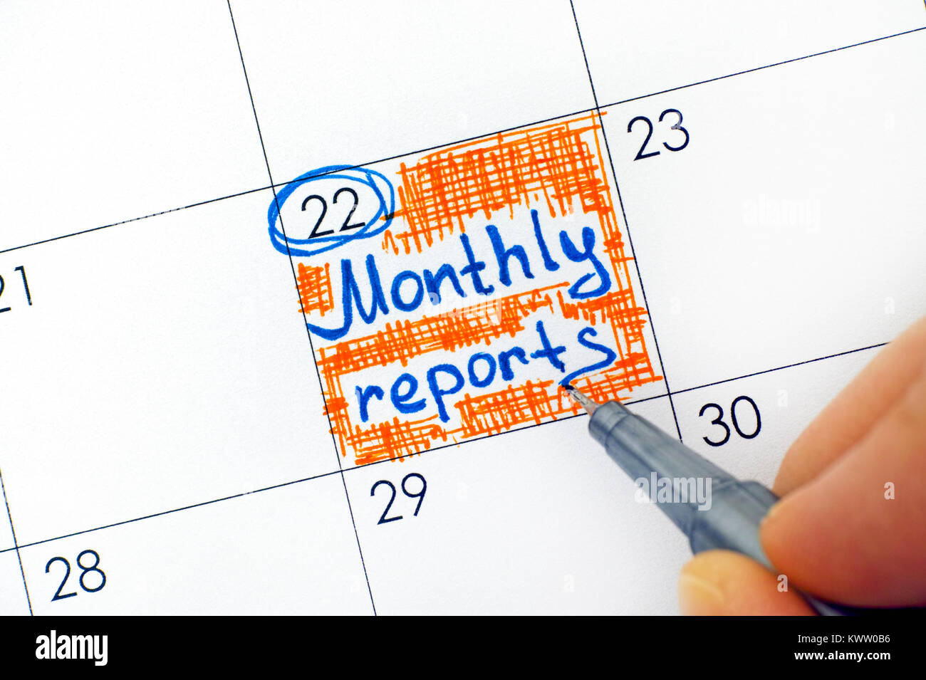Donna mano con una penna blu promemoria di scrivere relazioni mensili in calendario. Close-up. Foto Stock
