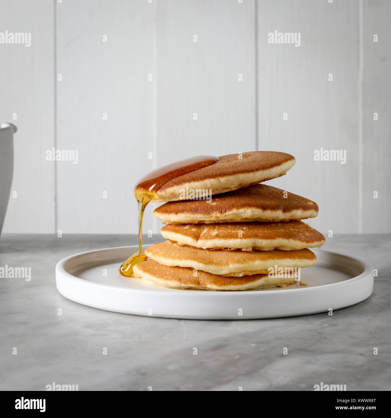 Una pila di frittelle con un gocciolamento lento del miele Foto Stock