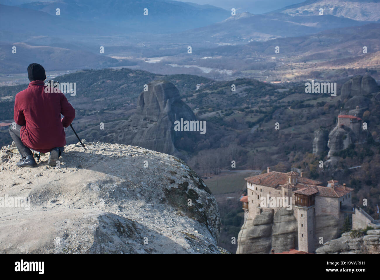 Traveler uomo fotografo professionale con telecamera e cavalletto, in corrispondenza di un bordo di una scogliera alta, prende le immagini di enormi rocce e i monasteri di Meteora Foto Stock