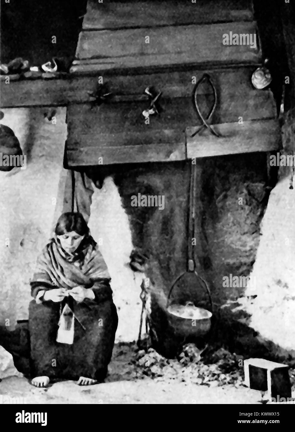 1921 Un Irish contadina la cottura su un fuoco di torba nel suo cottage Foto Stock