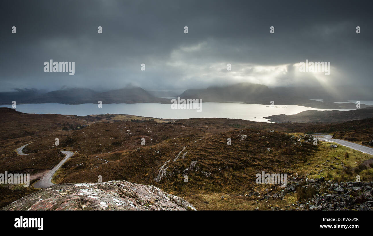 Alberi del burst di luce attraverso le nuvole sopra la zona di Torridon nelle Highlands scozzesi Foto Stock