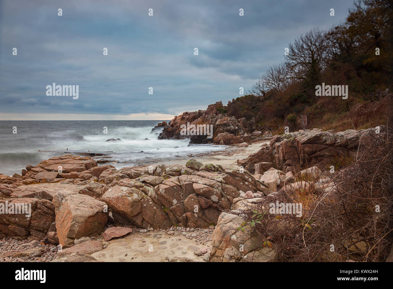 Una lunga esposizione di tempestoso tramonto a spiaggia rocciosa. Kullaberg, Svezia. Foto Stock