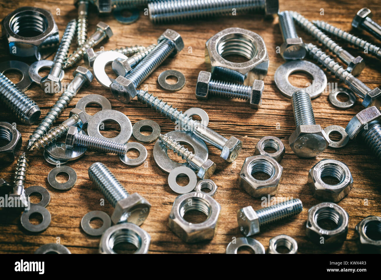 Le viti e i dadi su una superficie in legno Foto Stock