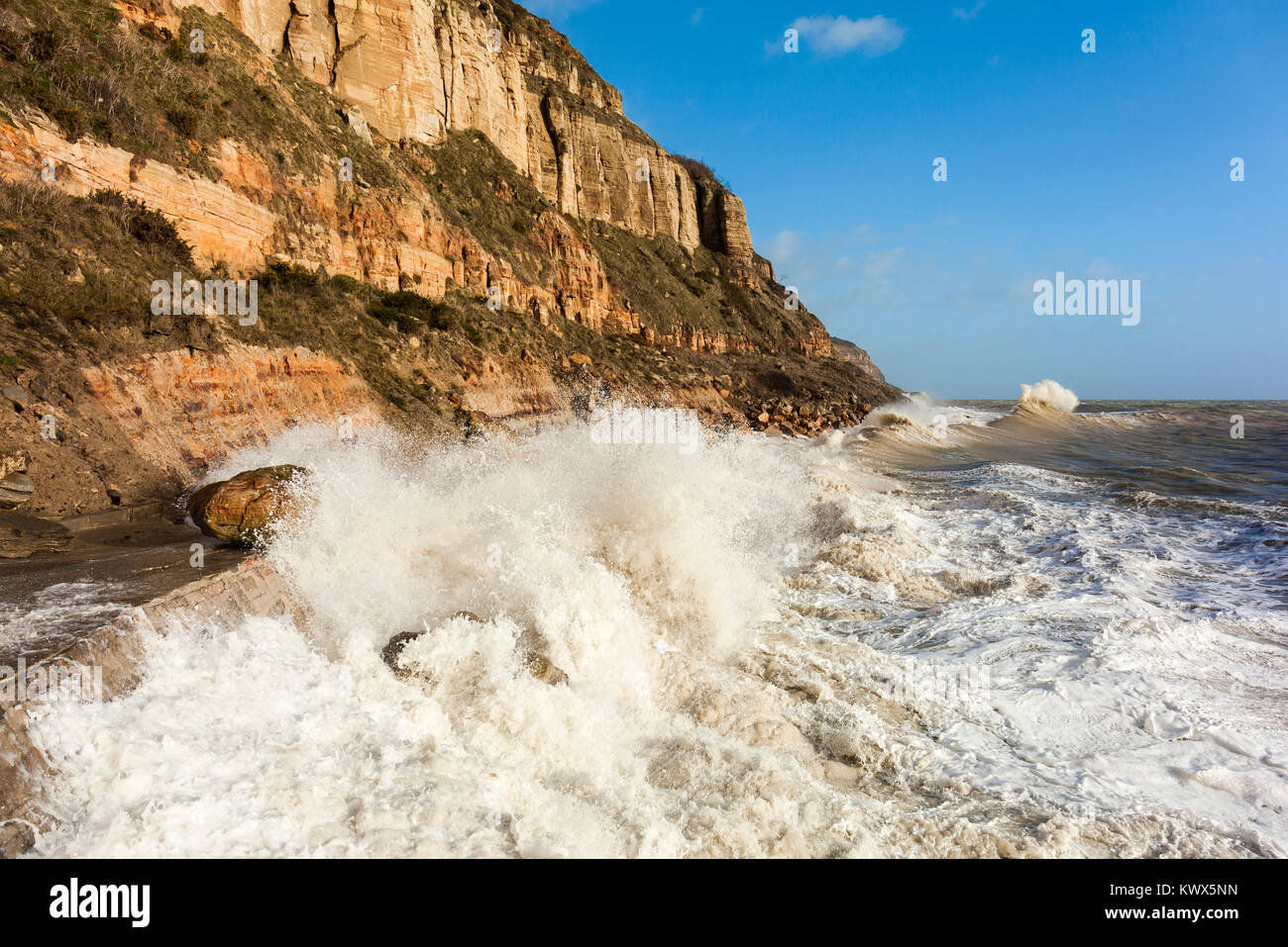 Tempesta di marea pounding in arenaria Oriente scogliere a Hastings. Foto Stock