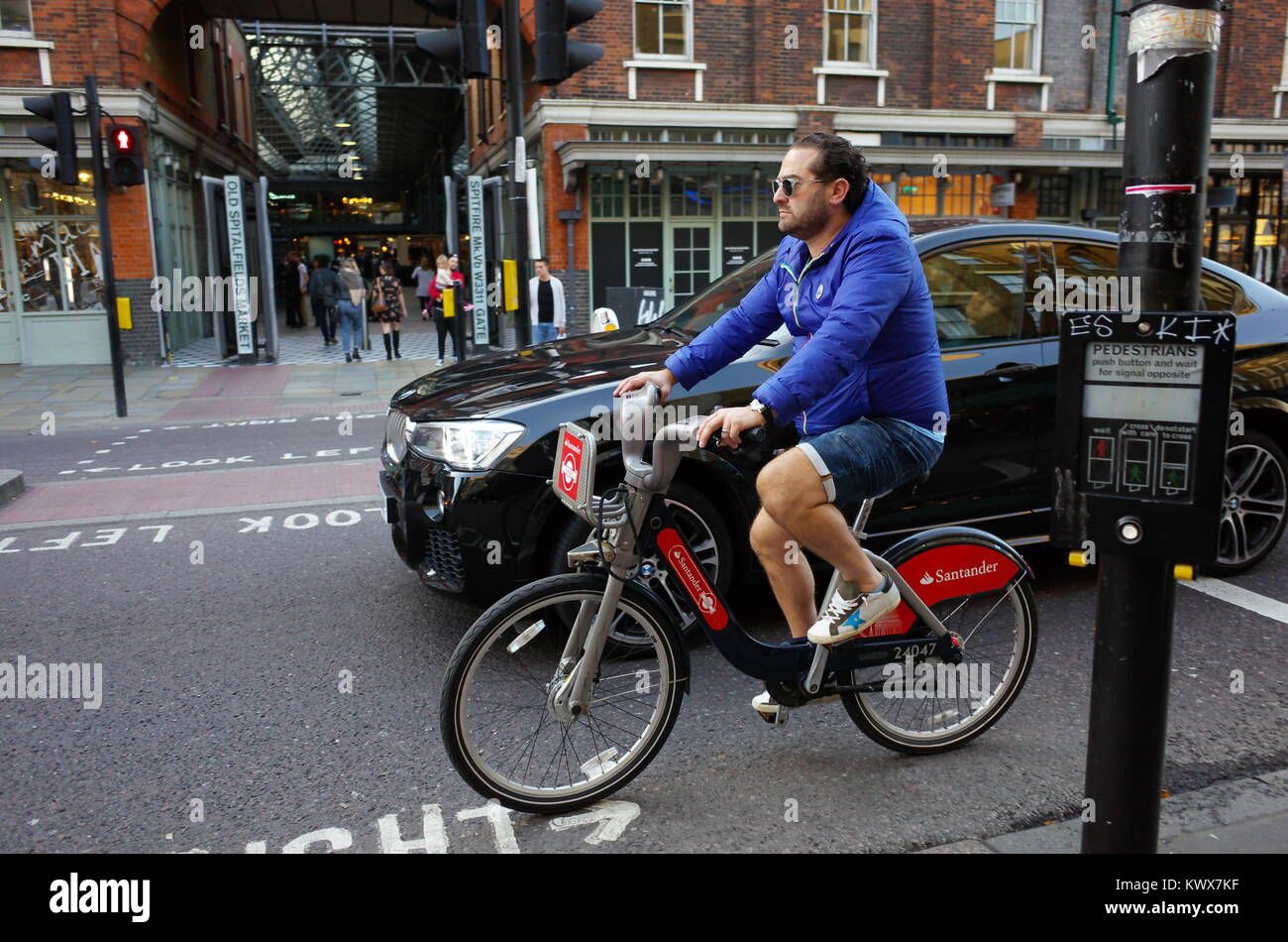 Ciclista equitazione noleggio bici a fianco di BMW auto in Shoreditch, Londra, Inghilterra Foto Stock