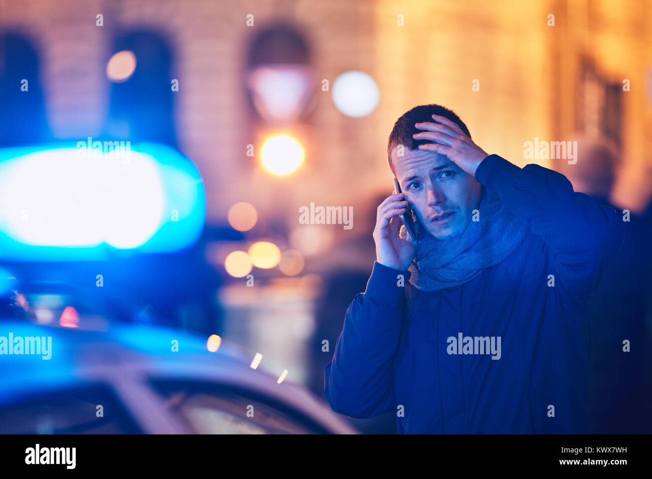 Giovane uomo della chiamata dopo una situazione di crisi sulla strada della citta'. Temi crimine, il servizio di emergenza medica, la paura o la guida. Foto Stock