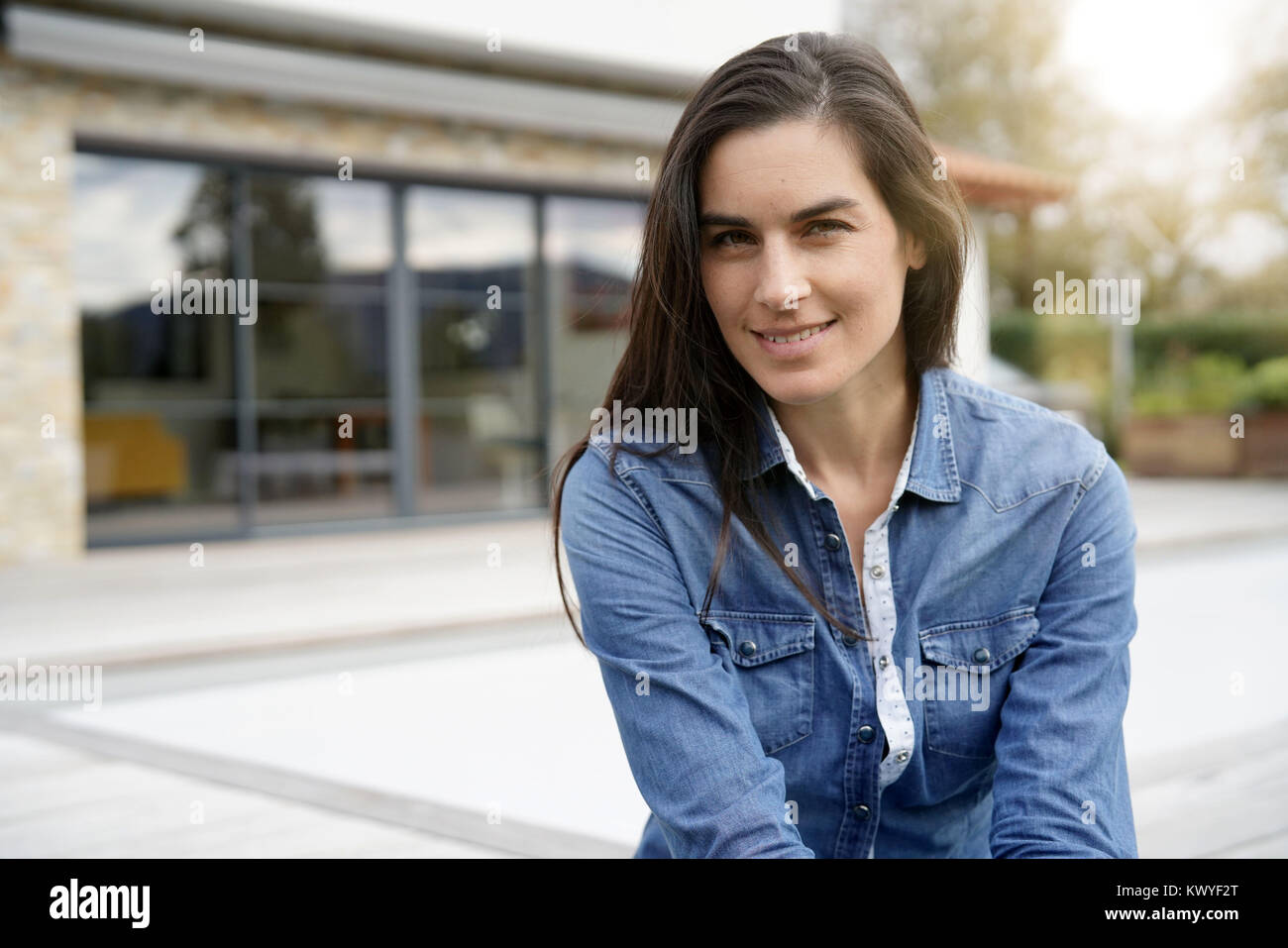Di mezza età donna seduta al di fuori di fronte a casa Foto Stock