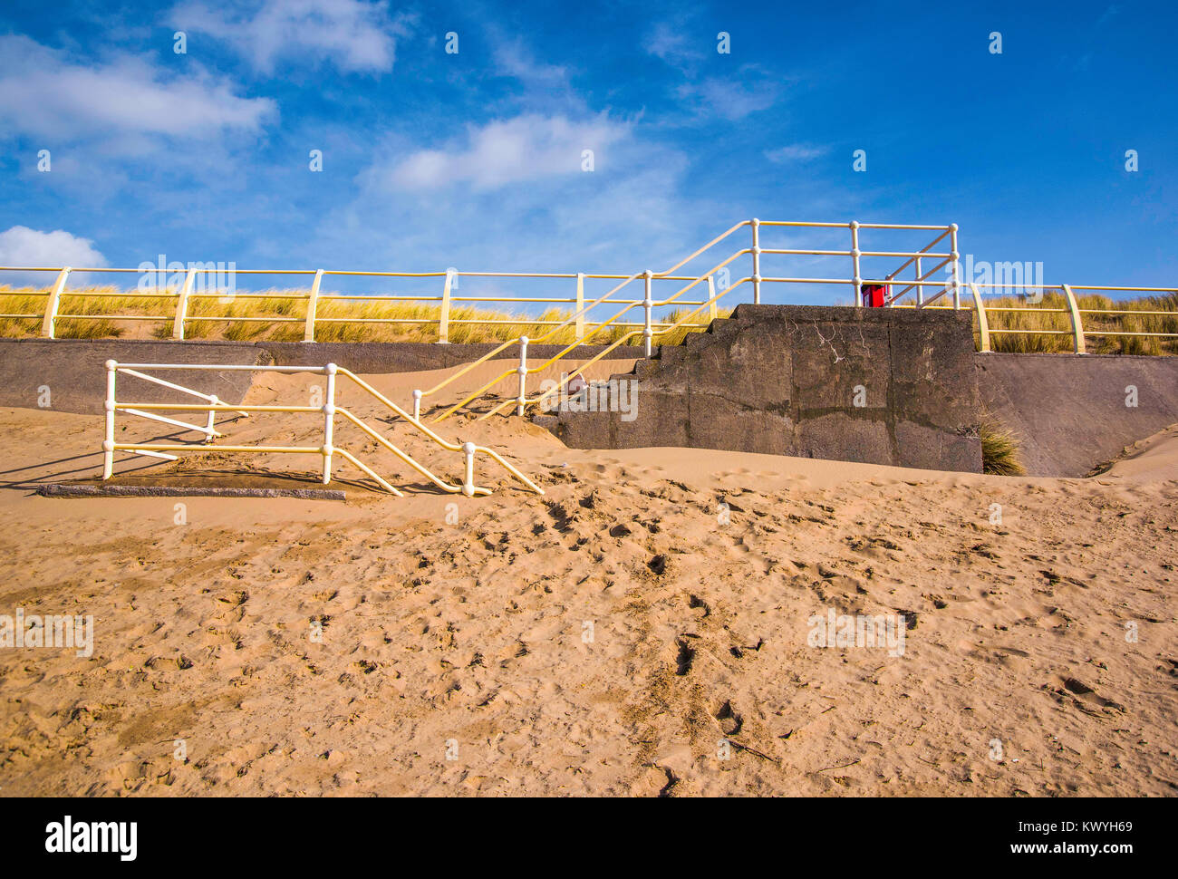 Vento-controllato sabbia ammucchiati contro la spiaggia i gradini di accesso di un mare parete in corrispondenza di Aberavon Beach, South Wales, Regno Unito. Foto Stock