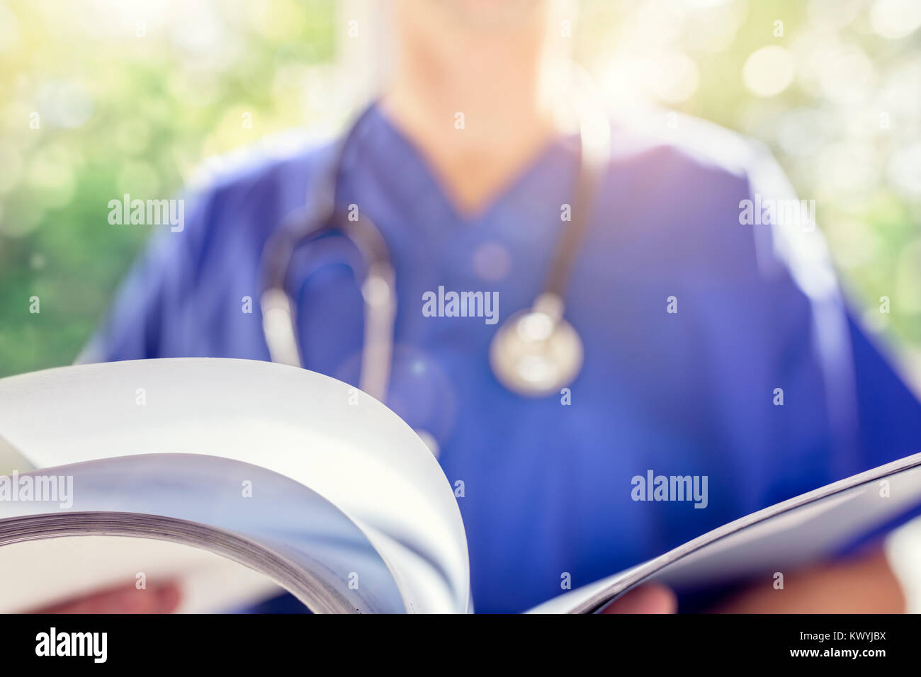 Dottore in scrubs uniforme di leggere le note sul paziente o diagramma di medico Foto Stock