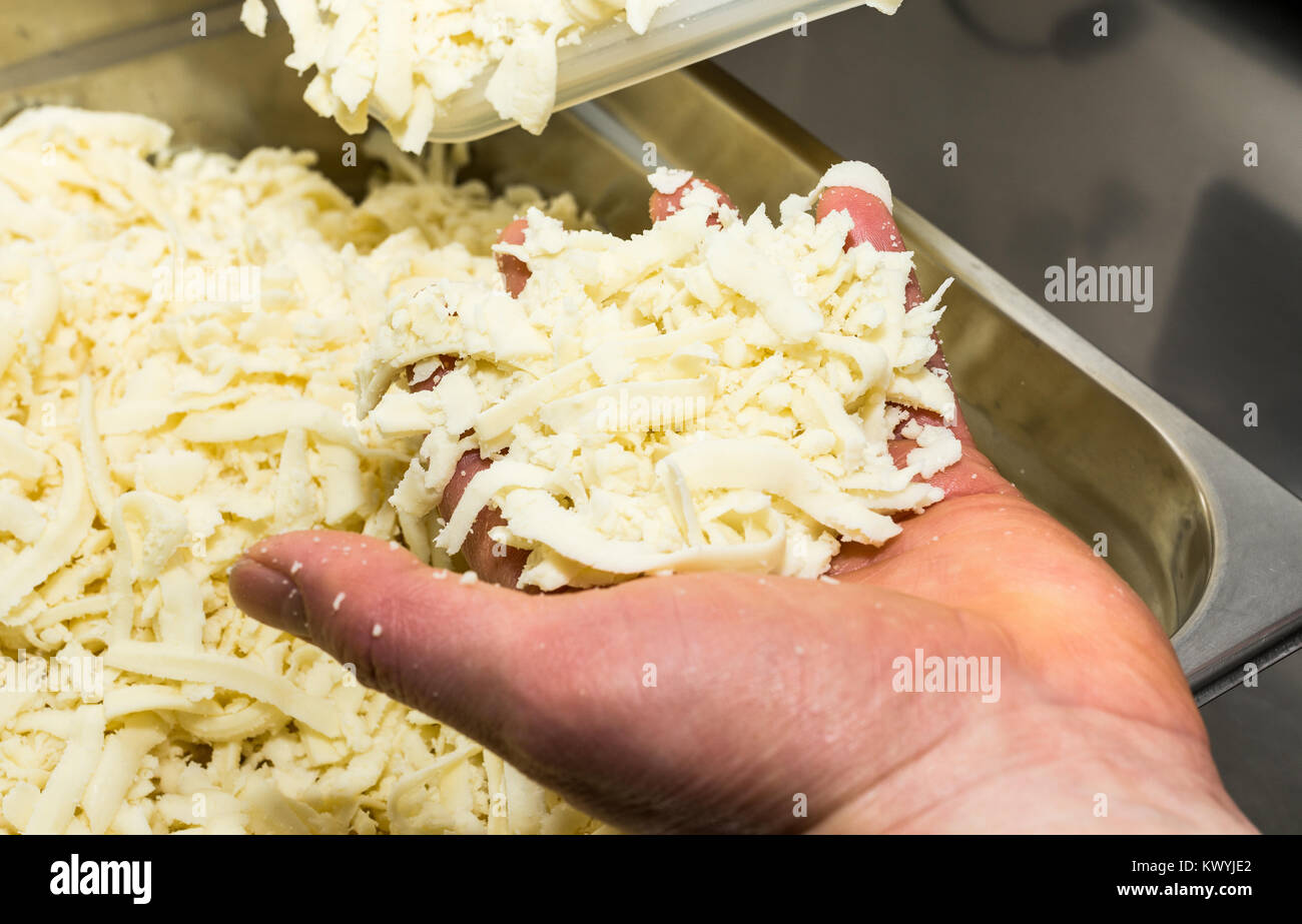 Tagliate il formaggio per pizza preparazione. Il cibo e la cucina italiana e il concetto di cucina a vista. Foto Stock