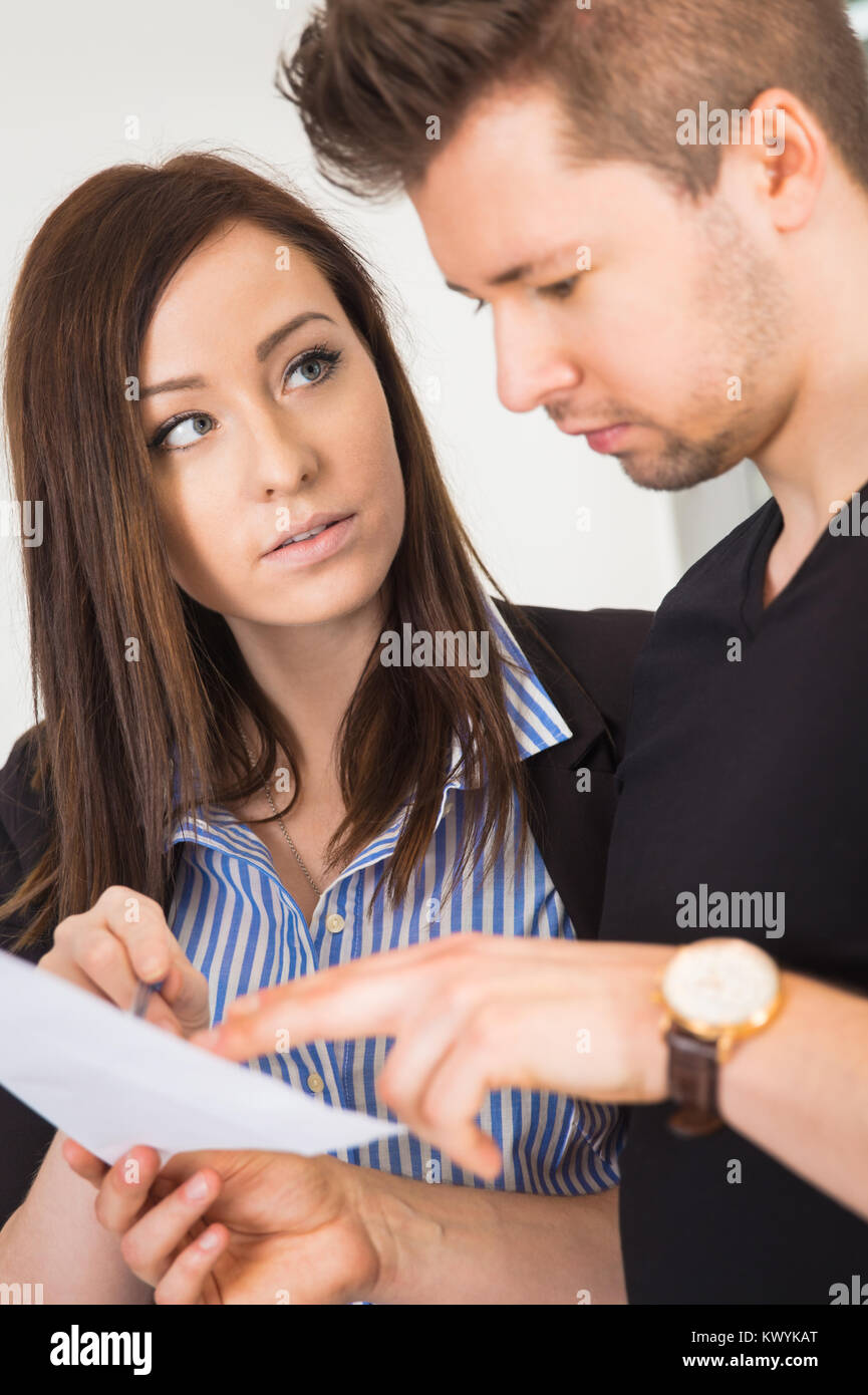 Imprenditrice guardando il collega di sesso maschile di documento di lettura Foto Stock