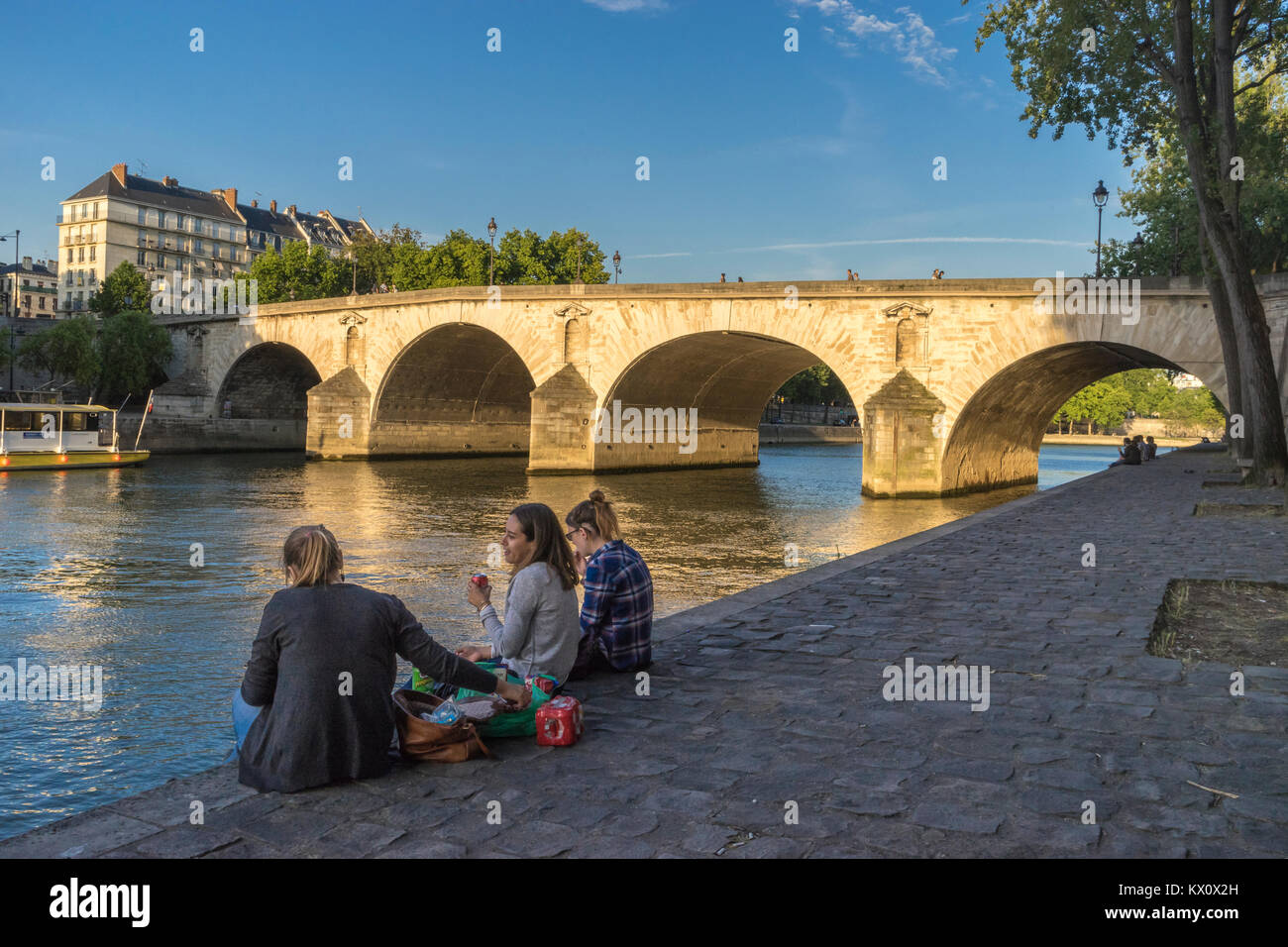Francia, Parigi (75), Donna fare picnic sul Quai de Bourbon con il Pont Marie dietro Foto Stock